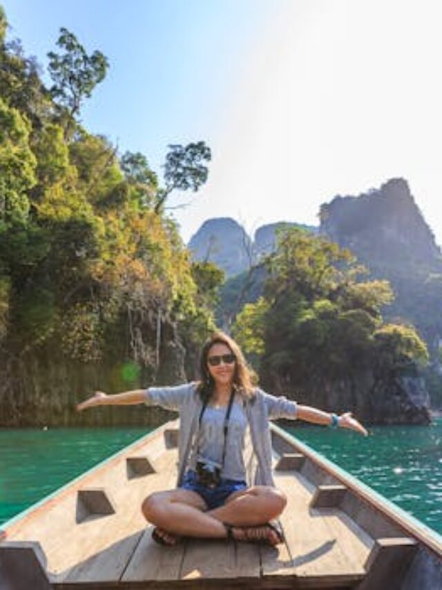 Asian woman relishing a serene boat journey through the lush karst landscape of Thailand's Khlong Sok.